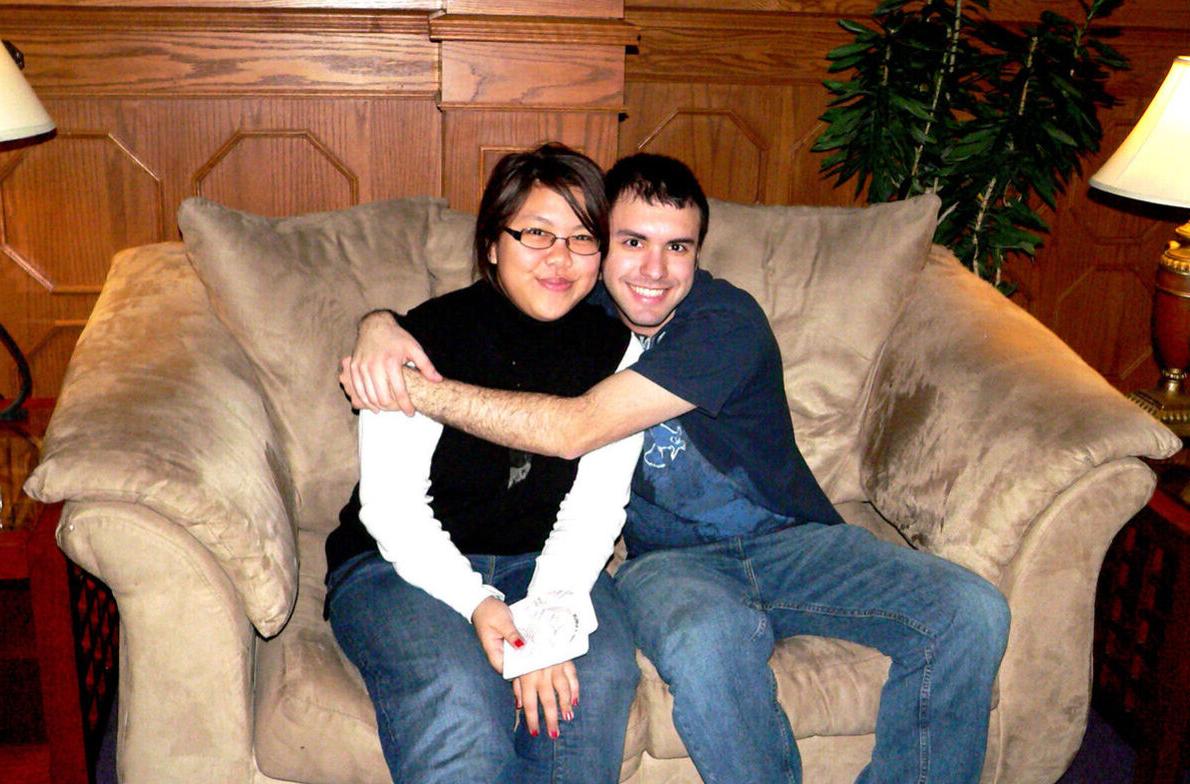 一名男学生拥抱一名女学生，两人都坐在一张毛绒椅子上